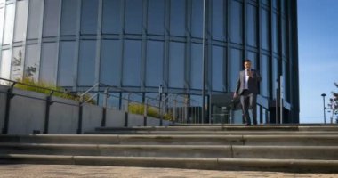 Bir iş merkezinde takım elbiseli bir işadamı çantayla binaya girer..