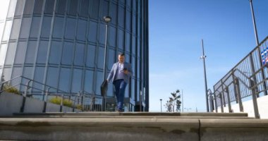 Başarıyı kutluyoruz. Heyecanlı genç işadamının kollarını havada tutması ve arka planda ofis binasıyla dışarıda durarak pozitifliğini ifade etmesi düşük açılı bir bakış açısı.