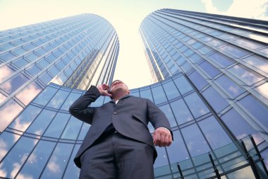 İş adamı internetten alışveriş yapmak için kredi kartı ya da internet kullanıyor. Arkaplanda bankacılık, iş dünyası, iş merkezinin gökdelenleri kavramı.