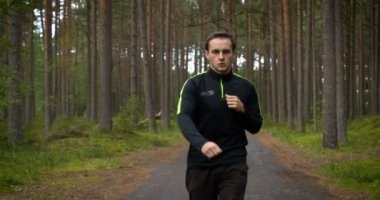 Ormanda koşan genç bir delikanlı. Koşucu doğada egzersiz yapıyor. Sağlıklı yaşam tarzı. eğitim ve idman.