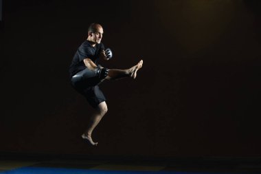 Siyah giysili bir adam bir atlama bir tekme atıyor.