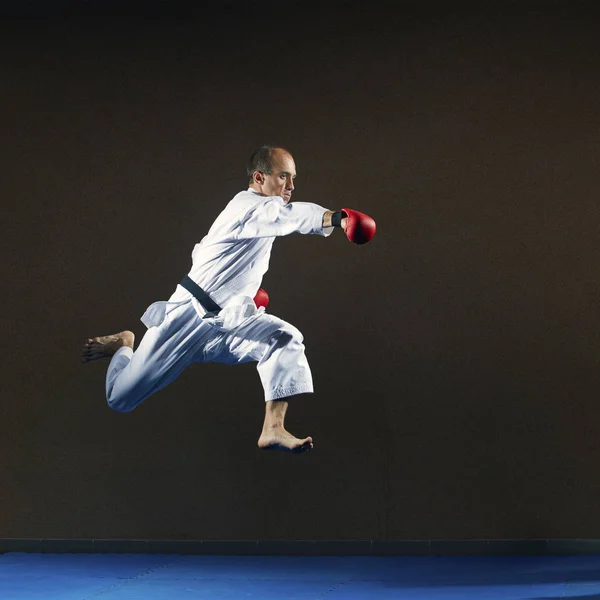 一个在 Karategi 的人用一只手在跳跃中罢工 — 图库照片