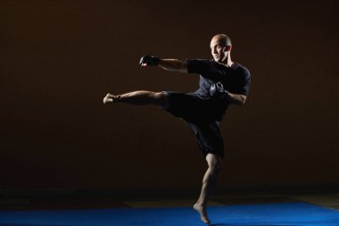 Bir adam siyah eldiven ve siyah tişört tekme bacak atıyor