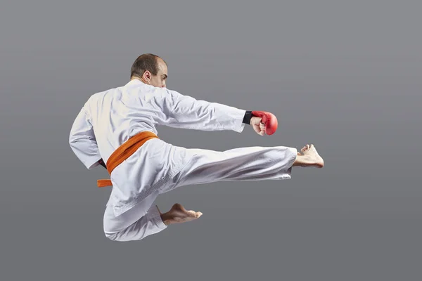 With an orange belt, an athlete beats a kick in a jump