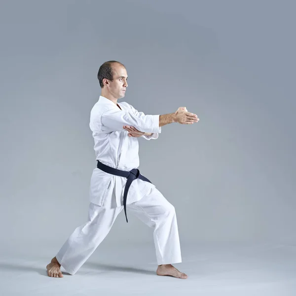 Jonge Atleet Doen Formele Karate Oefeningen Een Grijze Achtergrond — Stockfoto