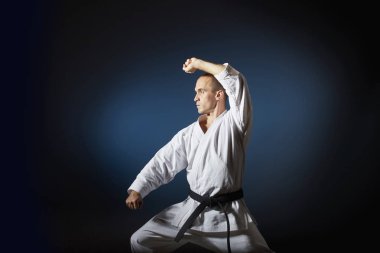 Bir degrade yetişkin sporcu ile mavi bir arka plan resmi karate çalışmaları gerçekleştirir.
