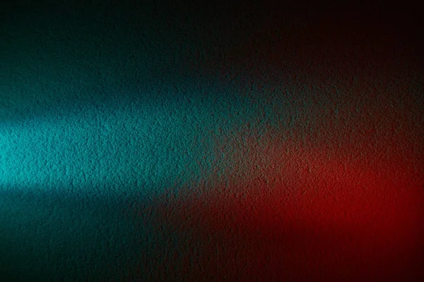 A ray of light and a dark red spot on a dark turquoise background