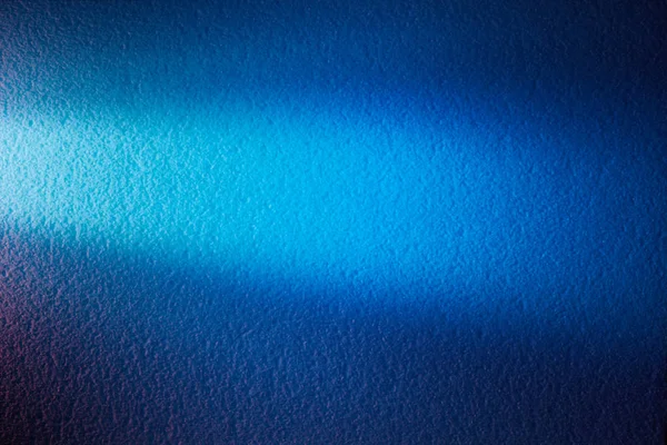 Bright light blue ray of light on a textural background of blue