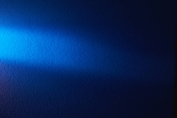 A beam of light blue light horizontally shines on a blurry textural blue background