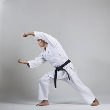 Aktif yetişkin atlet gri arka planda resmi karate egzersizleri yapıyor