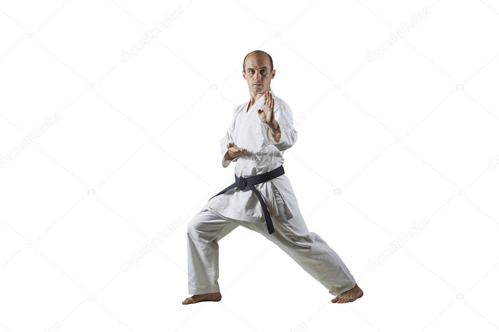 Adult athlete trains formal karate exercises on white isolated background