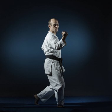 Mavi tatami adam üzerinde resmi karate egzersizleri gerçekleştirir