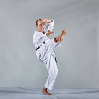 Karategi olarak, bir atlet gri bir arka plan üzerinde resmi karate egzersizleri gerçekleştirir