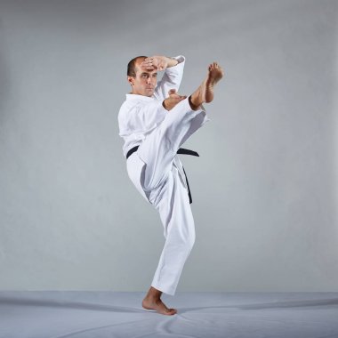 Gri bir arka plan üzerinde, karategi bir atlet resmi karate egzersizleri yapar