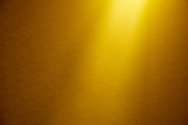 Açık sarı bir ışık demeti koyu sarı ince dokulu arka plan yukarıdan yanar.