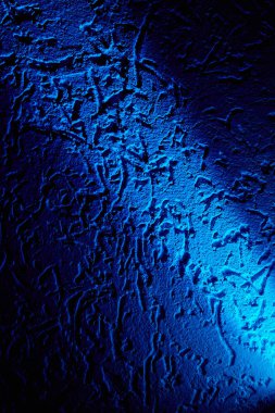 Açık mavi bir ışık ışını, koyu mavi bir arka planı desenlerle çapraz olarak aydınlatır