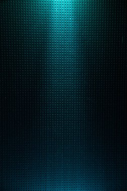 Yukarıdan açık turkuaz ışık demeti ile aydınlatılan noktaya koyu turkuaz arka plan