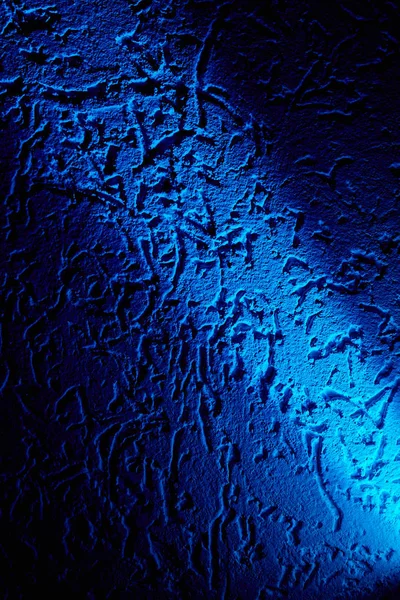 Açık mavi bir ışık ışını, koyu mavi bir arka planı desenlerle çapraz olarak aydınlatır