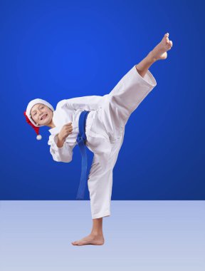 Mavi kemerli bir sporcu ve Noel Baba şapkası tekmeliyor.