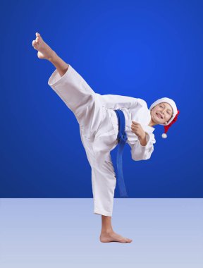 Noel Baba şapkasındaki Karateka mavi arka plana tekme attı