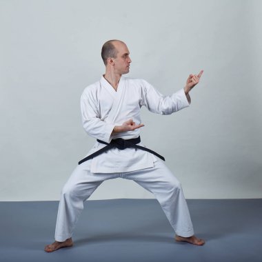Gri kapaklı karategi giyen bir adam resmi karate egzersizleri yapıyor.