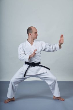 Karategi 'deki bir adam gri kapaklı resmi karate egzersizleri yapıyor.
