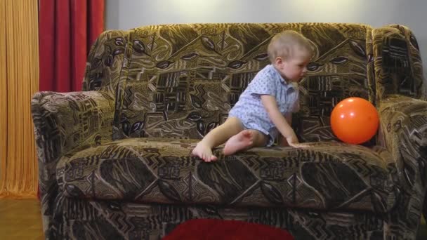 Niño Jugando Con Una Bola Naranja Sofá — Vídeos de Stock