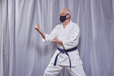 Yaşlı atlet kendini izole etme konusunda resmi karate egzersizleri yapıyor.
