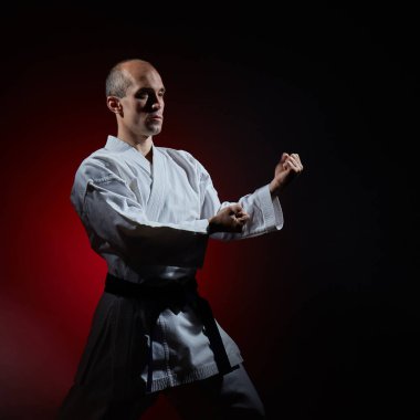 Genç atlet kırmızı gradyan üzerinde karate duruşunda duruyor