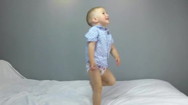 Gri arka planda neşeli iki yaşında bir bebek.