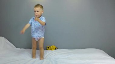 Gri arka planda dans eden iki yaşında bir çocuk.