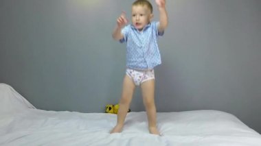 Gri arka planda dans eden iki yaşındaki bir çocuk.