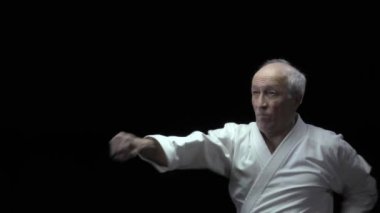 Karate duruşunda, yaşlı bir atlet blokları eğitir ve kolları yumruklar.