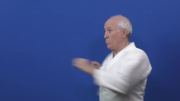 Синьому Тлі Каратегі Старий Спортсмен Тренує Удари Блоки Своїми Руками — стокове відео