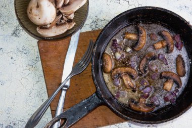 Kavrulmuş petrol mantar ahşap tahta üzerinde bir tavada soğan ile.