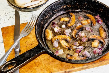 Kavrulmuş petrol mantar ahşap tahta üzerinde bir tavada soğan ile.