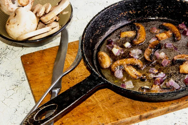 Kavrulmuş petrol mantar ahşap tahta üzerinde bir tavada soğan ile.