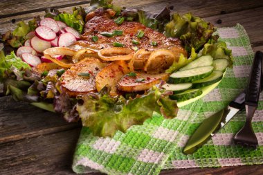 Kızarmış domuz eti biftek ile kızarmış patates, Lollo Rosso marul tabağa içinde turp ve salatalık dilimlenmiş soğan, kızarmış. Lezzetli yemekler. Ahşap arka plan.