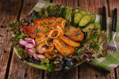 Kızarmış domuz eti biftek ile kızarmış patates, Lollo Rosso marul tabağa içinde turp ve salatalık dilimlenmiş soğan, kızarmış. Lezzetli yemekler. Ahşap arka plan.