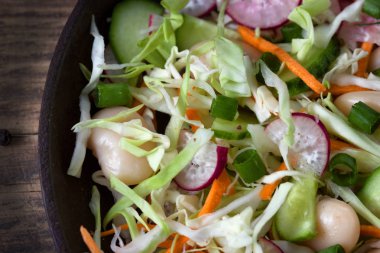 Diyet salata, salatalık, lahana, havuç, turp, büyük beyaz fasulye ve yeşil soğan zeytinyağı bir plaka üzerinde bir metal arka plan ile. Düz yatıyordu. Üstten görünüm. Sebze salatası. Sağlıklı gıda, diyet, detoks ve vejetaryen kavramı. 