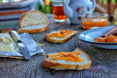 Lezzetli kahvaltı. Kayısı reçel, reçel, tereyağı, bir fincan çay ile ekmek erken kahvaltı için dilimlenmiş