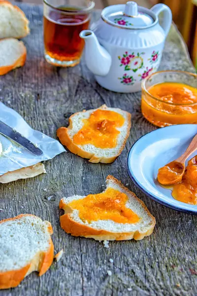 Lezzetli kahvaltı. Kayısı reçel, reçel, tereyağı, bir fincan çay ile ekmek erken kahvaltı için dilimlenmiş