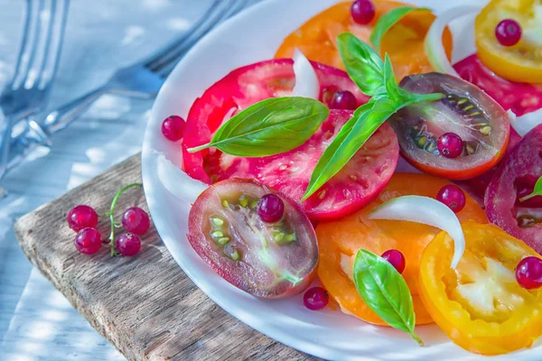 スライスした新鮮なカラフルなトマトのおいしい夏サラダ 白いレーズン オリーブ オイル バジルと赤タマネギのみじん切り 健康的な食事 — ストック写真