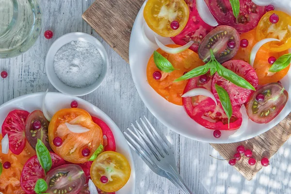 スライスした新鮮なカラフルなトマトのおいしい夏サラダ 白いレーズン オリーブ オイル バジルと赤タマネギのみじん切り 健康的な食事 — ストック写真