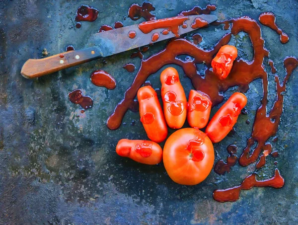 Cadılar Bayramı palm domates uzun bir domates, bir paslı eski bıçak üzerinden kesilen parmak ile tüm sahte kan domates sosu ile kaplı. Bir eski paslı demir arka plan üzerinde bir tatil için dekorasyon.