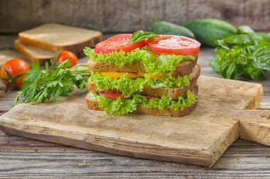 Sandviç taze renkli domates, marul, fesleğen ve ahşap arka plan üzerinde eski masa üzerine krem peynir ile