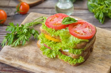 Sandviç taze renkli domates, marul, fesleğen ve ahşap arka plan üzerinde eski masa üzerine krem peynir ile