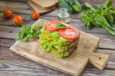Sandviç taze renkli domates, marul, fesleğen ve ahşap arka plan üzerinde eski masa üzerine krem peynir ile