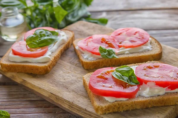 Crostini with toasted gray bread, cottage cheese and slased tomatoes , lay old desk on wooden textured background