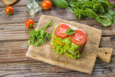 Sandviç taze renkli domates, marul, fesleğen ve ahşap arka plan üzerinde eski masa üzerine krem peynir ile